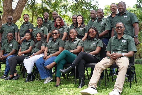 Group of people wearing matching green shirts outdoors.
